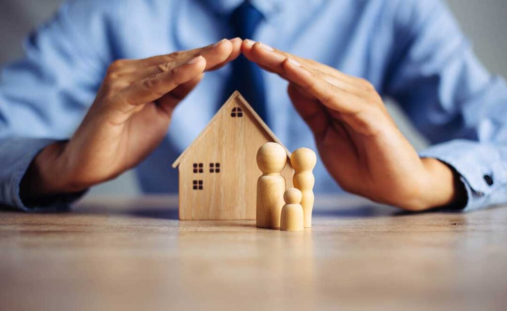 A couple reviews household expenses, debts, and insurance documents at a kitchen table.